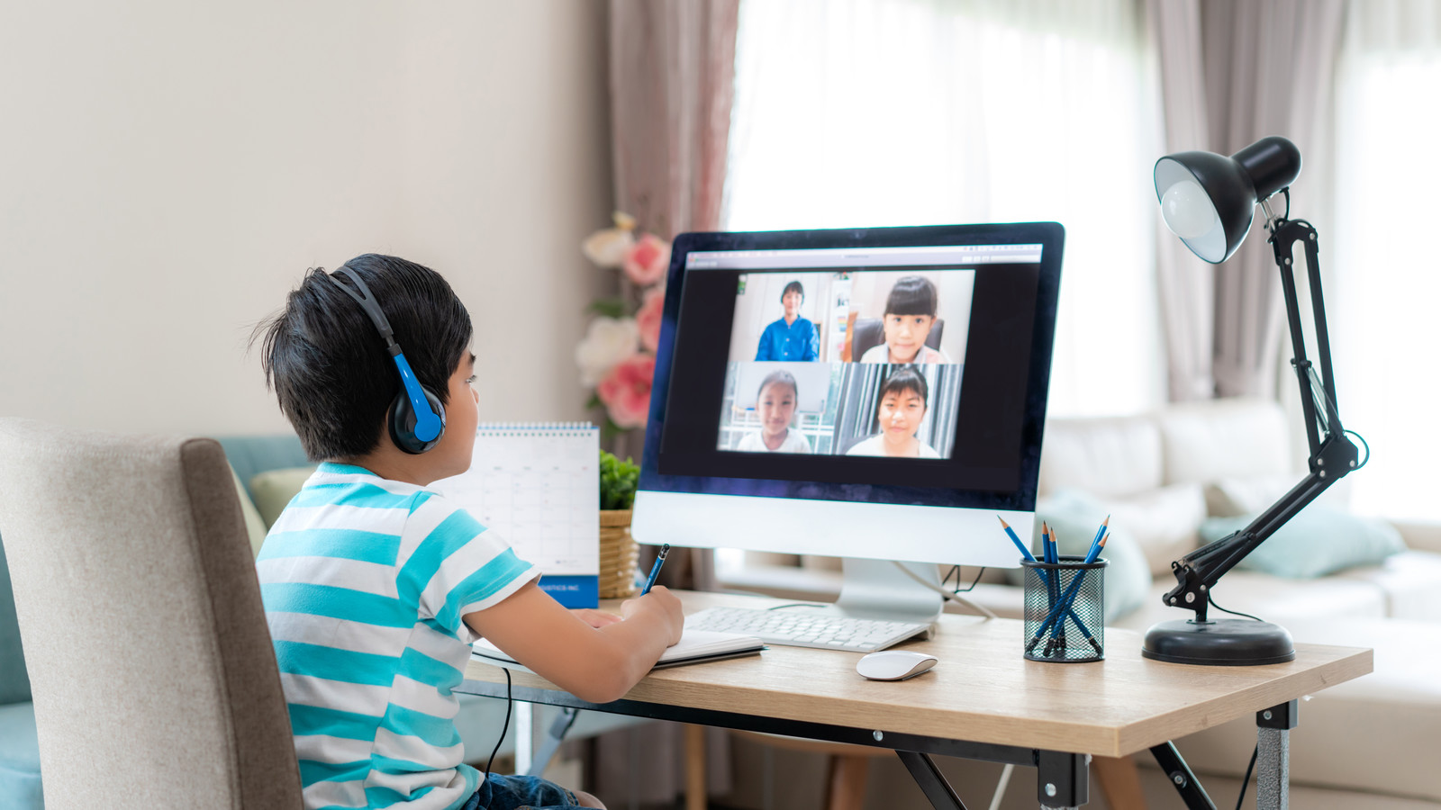 Asian boy student video conference e-learning with teacher and classmates on computer in living room at home. Homeschooling and distance learning ,online ,education and internet.