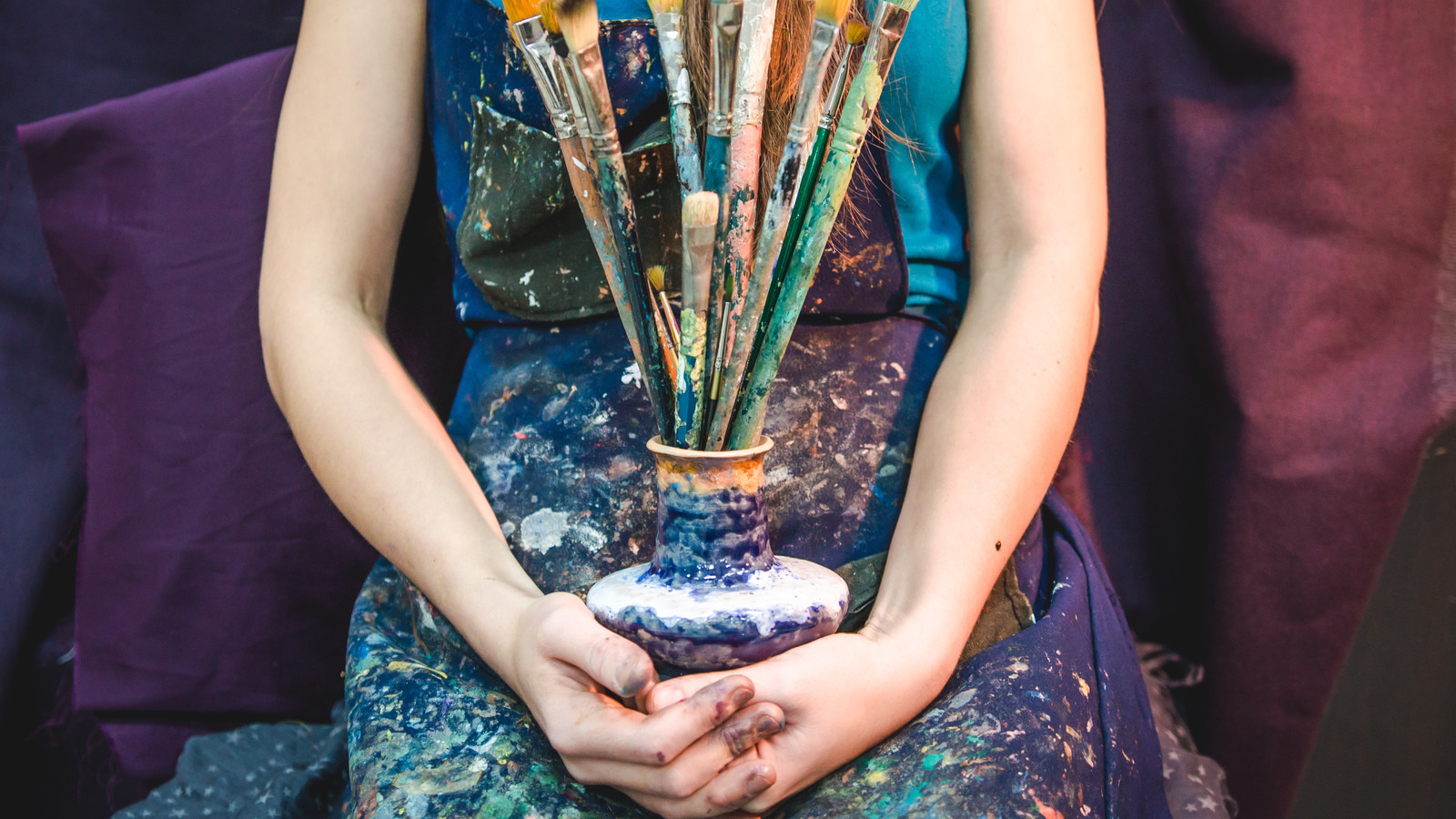 Closeup of female artist hands with paintbrushes
